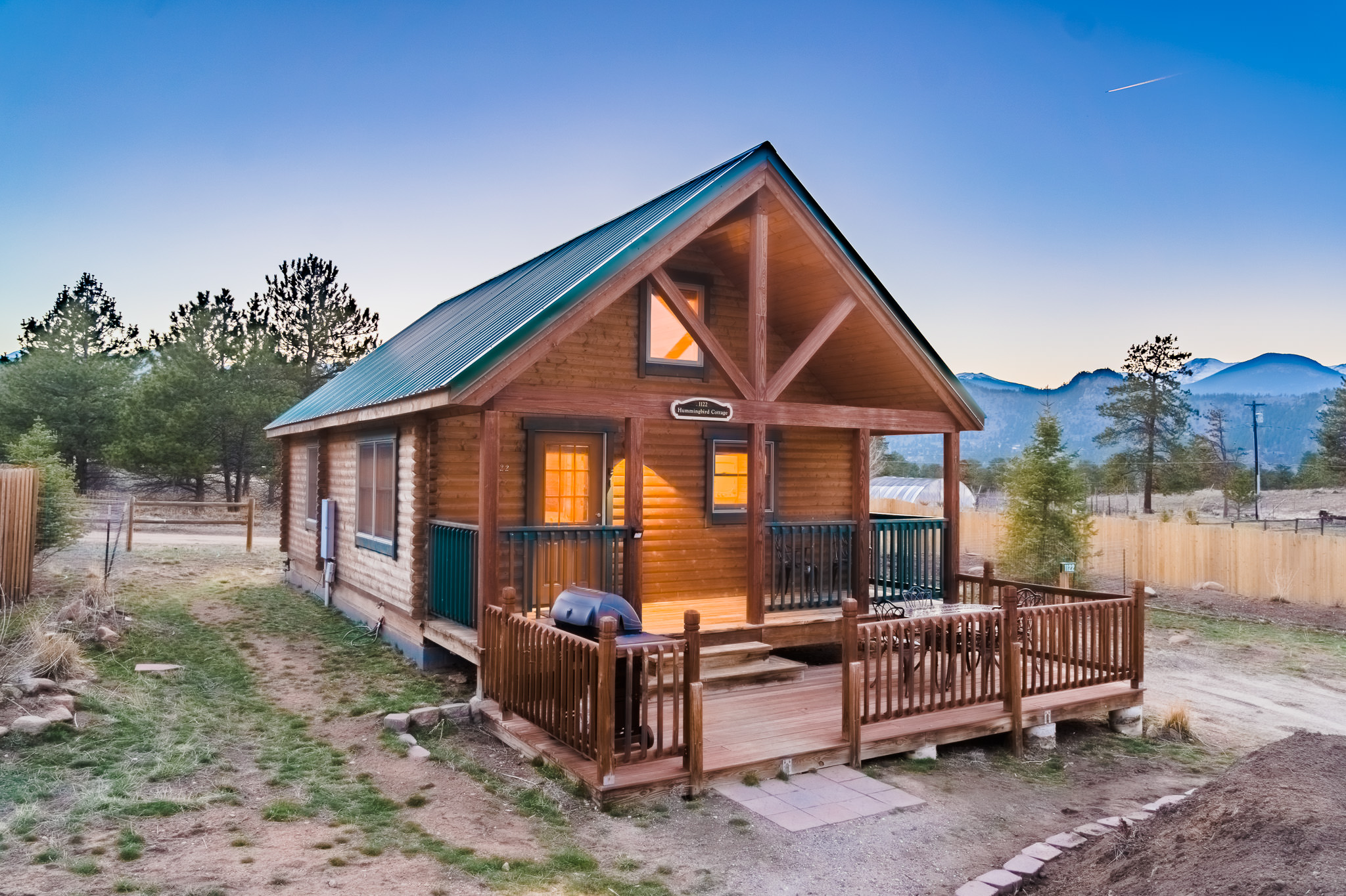A small timber cabin with warm windows and a covered porch at dusk.