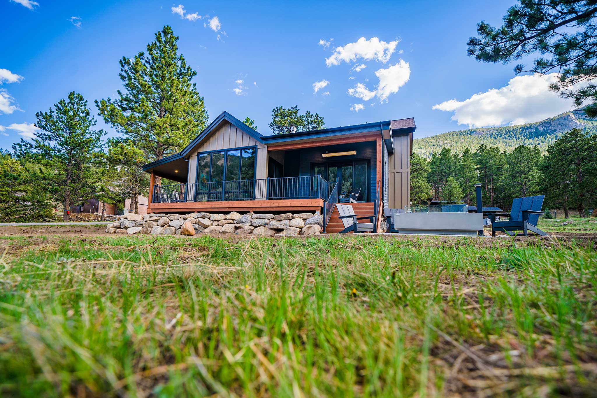 A compact modern cabin with large windows and a patio in the pines.