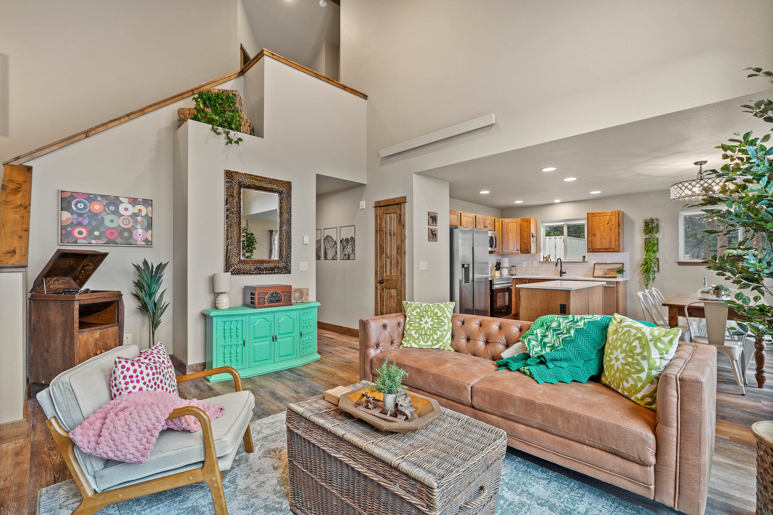 A bright living room with a leather sofa, colorful textiles, and a mint-green cabinet.
